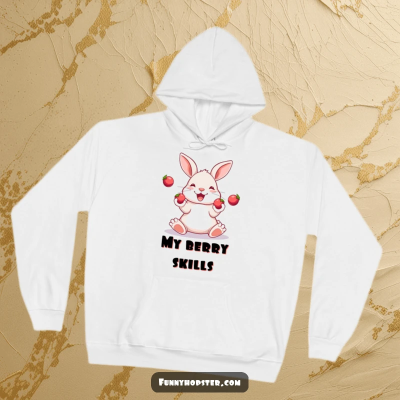 Funny hoodie of a happy rabbit skillfully juggling three shiny berries with its paws, looking focused and delighted.